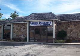 A sturdy, traditional stone and timber commercial building in a small Tennessee town at golden hour. The building features large warm windows, a solid stone facade, and a rustic yet professional architectural style. It evokes a sense of stability, permanence, and community stewardship, fitting for a trusted local insurance agency.